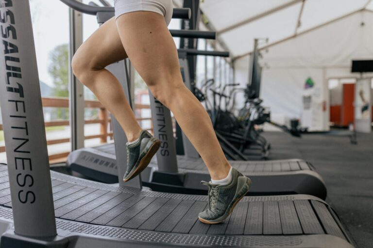 A woman running on a treadmill in a home gym represents an article about recommendations for preventing stress fractures from running or exercising at home.